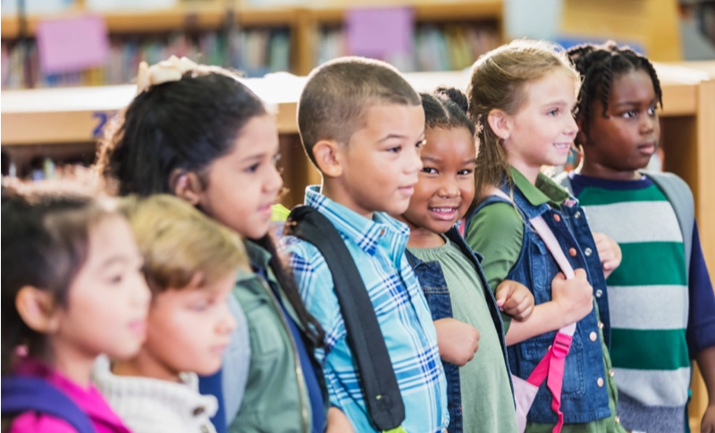 A diverse group of young students standing together in a school library